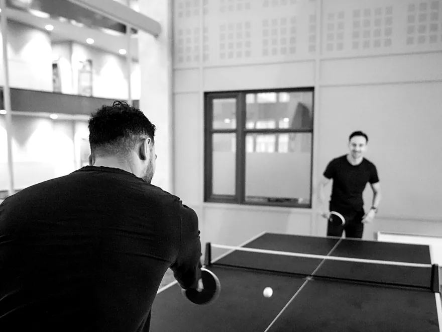 To kolleger spiller bordtennis i pausen ved pingpongbordet på kontoret.